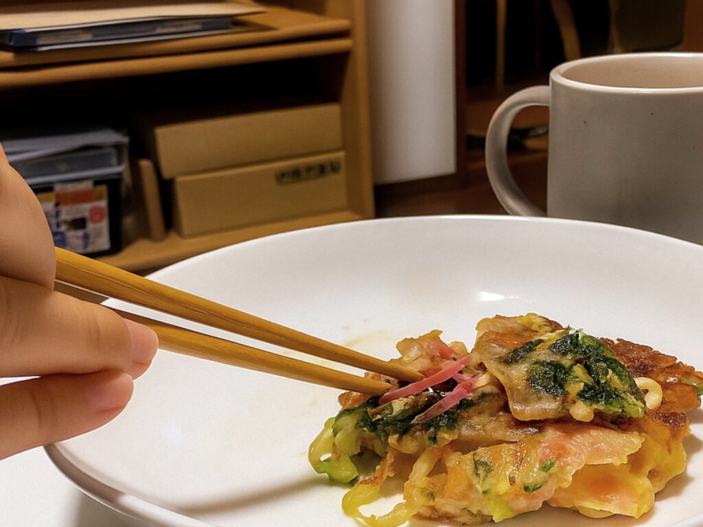 ナナが箸でお好み焼きつつく様子